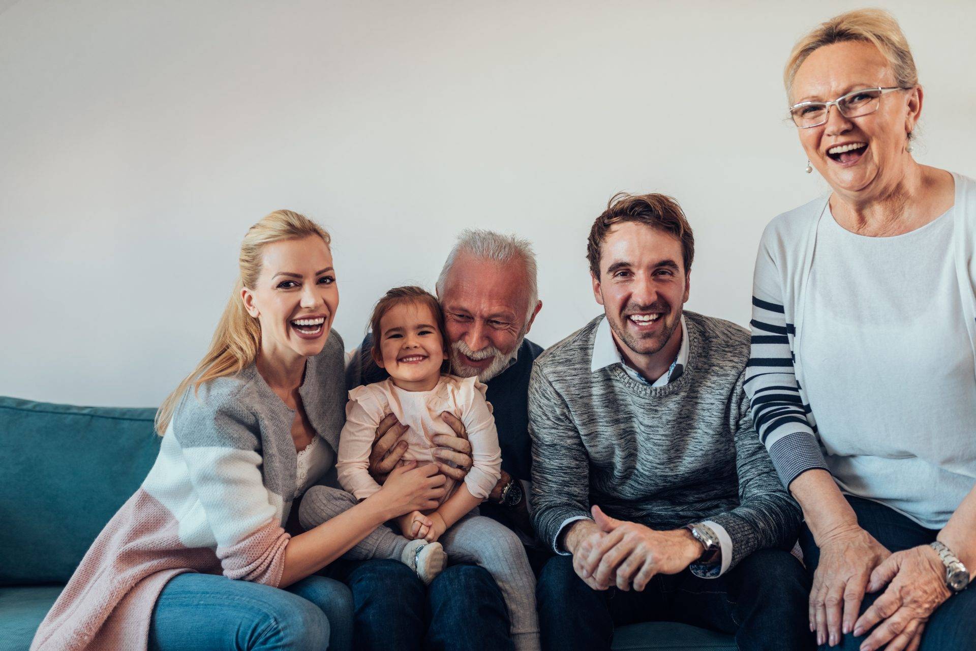 A family sits on a couch and smiles.