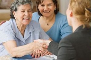 Elderly woman shaking hands with a professional, accompanied by another woman, at a desk.
